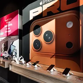 Smartphone-Ausstellung mit iPhone Pro Werbung und mehreren Handys in einem Elektronikladen.