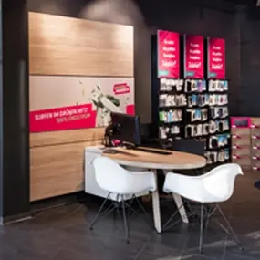 Modernes Telekommunikationsgeschäft mit Beratungstisch, Regalen und Werbetafeln.