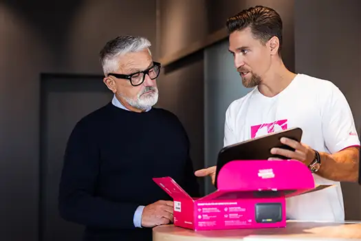 Mitarbeiter berät Kunden zu Telekom Router und Internet im Shop am Tresen