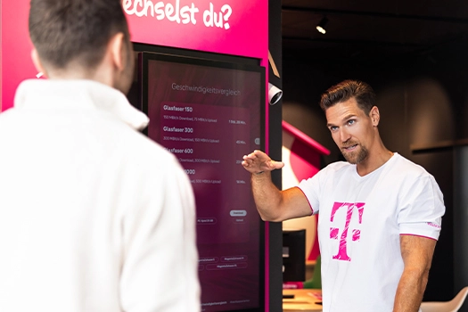 Ein Telekom-Mitarbeiter berät einen Kunden zu Glasfaser-Tarifen im Telekom-Shop.