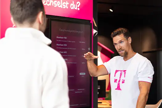 Telekom Mitarbeiter erklärt Tarifwechsel am digitalen Display im Shop